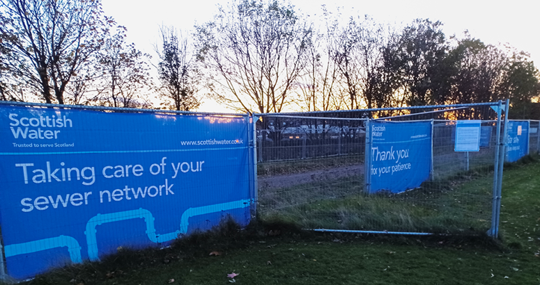 Park area with heras fencing with banners saying 'Taking care of your sewer network